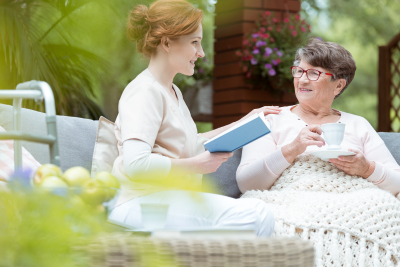 caregiver reading a book to a senior woman